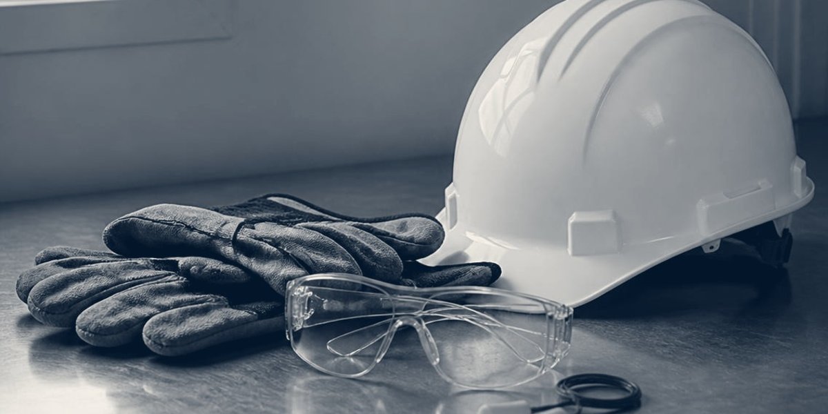 Elementos de protección personal sobre una mesa: casco, guantes y lentes de seguridad